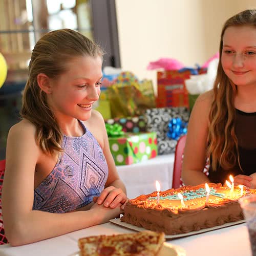 Teen girl looking at birthday cake at party at Avalanche Bay