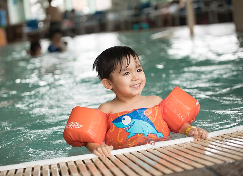 Toddler boy playing in zero-depth pool at indoor water park