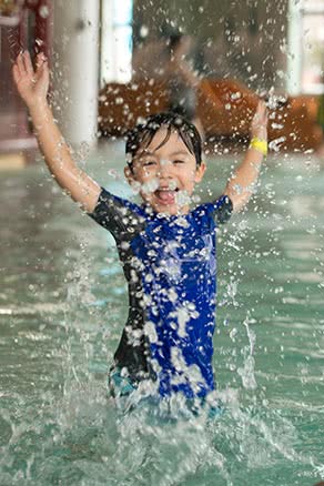 Toddler boy splashing in zero entry pool