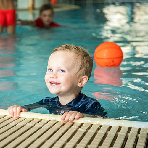 Young boy smiling in pool at indoor water park