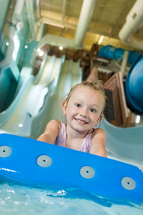 Toddler girl at bottom of mat racer slide at water park