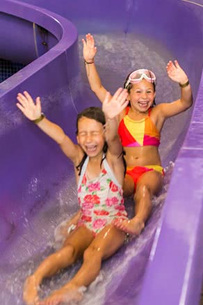 Kids with arms up on waterslide