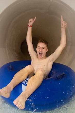 Boy with hands up on water slide