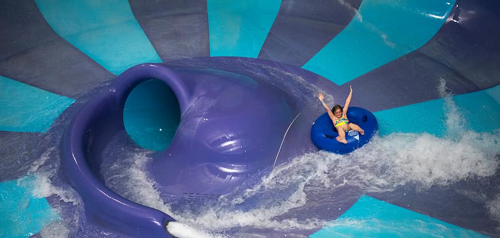 Girl with hands up on toilet bowl waterslide at Avalanche Bay